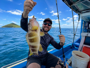 Host s ulovenou tropickou rybou na rybářské lodi