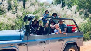 Účastníci Jeep Tour jedou otevřeným historickým džípem tropickou krajinou.