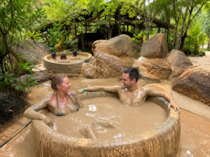 Návštěvníci relaxují v přírodních bahenních lázních obklopených tropickou zelení.