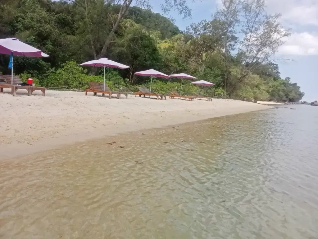 Relaxační zóna na písečné pláži s lehátky a slunečníky u klidného, mělkého moře na Phu Quoc.