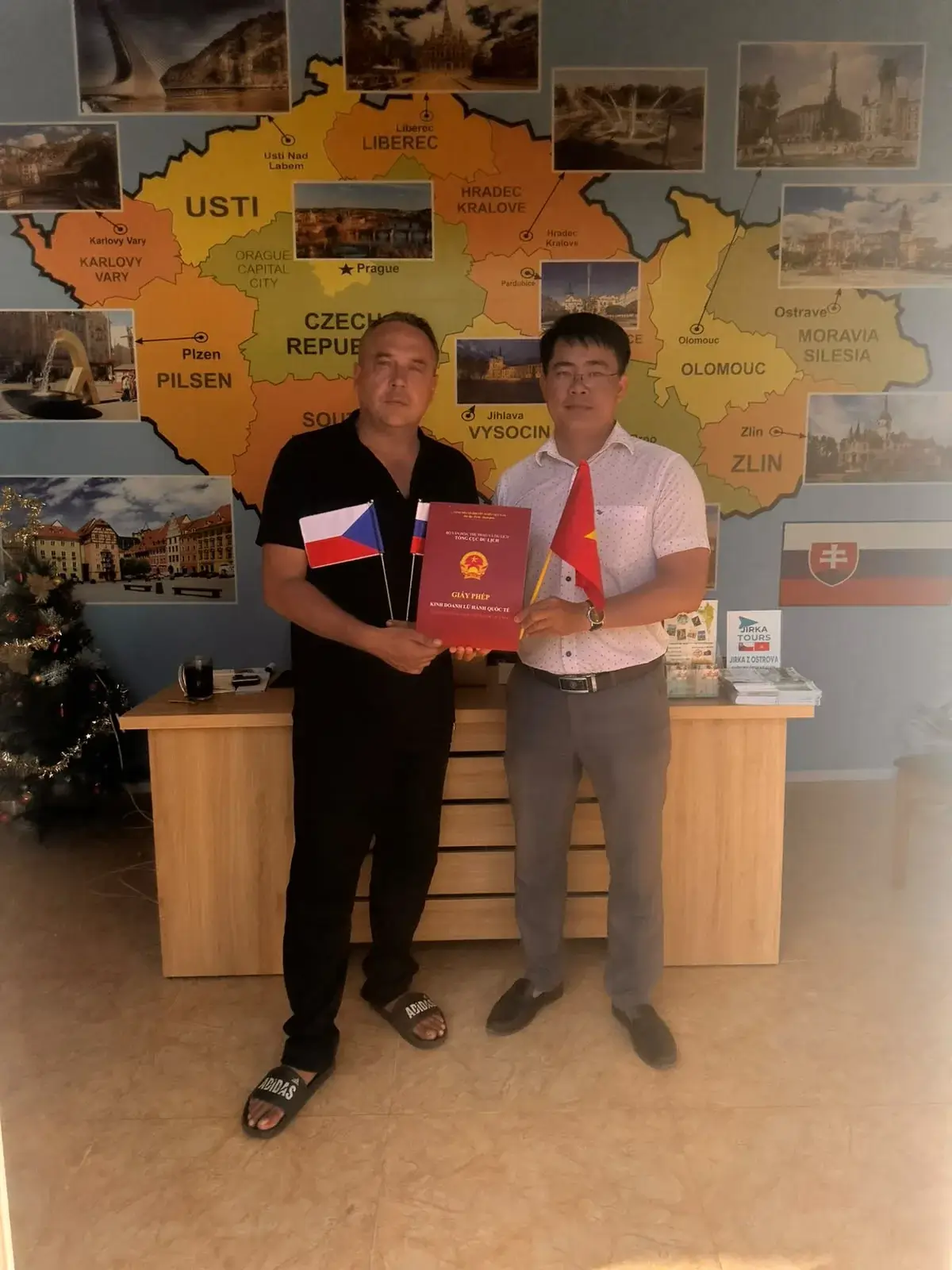Dva lidé s červenými deskami před mapou Česka